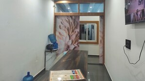 A hotel lobby with a reception desk, a large mirror, and a wall-mounted television. - Hotel Town Inn Near Railway Station (Mathura)