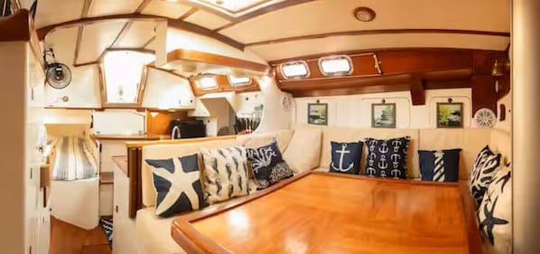 A cozy interior with a wooden dining table, cushioned seating, and nautical-themed decor.