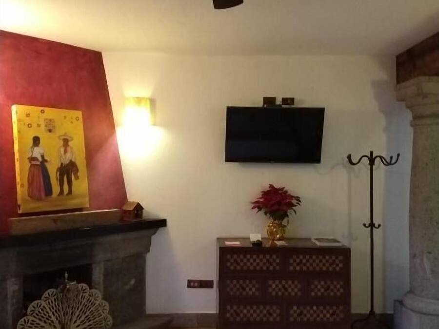 Ein Wohnzimmer mit Kamin, Deckenventilator, Wand-Fernseher und einem gemusterten Teppich.