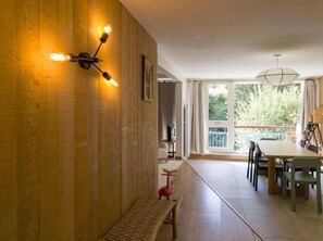 A modern interior with a wooden wall, a bench, a dining area with chairs and a table, and a view through a large window. - 300m from ski lifts, floor -3, tv, 74m², Les Arcs (Les Arcs)