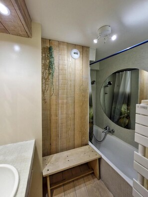 A bathroom with a wooden panel wall, a bench, a bathtub, and a mirror with a curved frame. - 300m from ski lifts, floor -3, tv, 74m², Les Arcs (Les Arcs)