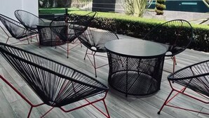 A modern outdoor seating area with black metal chairs and tables, surrounded by a well-maintained hedge and a pool. - Apartment in Cayala City/ 2 bedrooms, pet friendly / US Embassy (Ciudad de Guatemala)