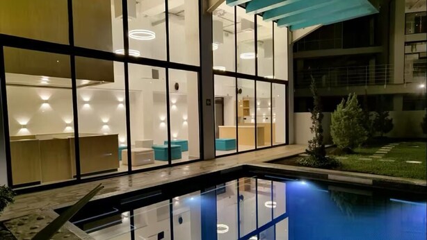 A modern building with a glass facade, a pool, and a well-lit interior. - Apartment in Cayala City/ 2 bedrooms, pet friendly / US Embassy (Ciudad de Guatemala)