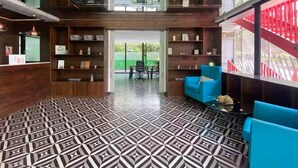 A modern lobby with a geometric patterned floor, wooden shelving with various items, and a blue sofa. - Apartment in Cayala City/ 2 bedrooms, pet friendly / US Embassy (Ciudad de Guatemala)