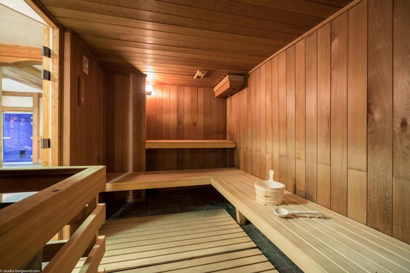 A wooden sauna with benches and a bucket.