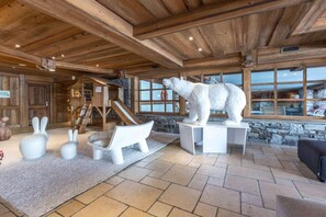 Ein Blockhaus-Interieur mit einer Steinwand, einer Holzbalkendecke und einer Eisbärenskulptur auf einem Sockel.