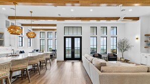 A spacious kitchen with a central island, wooden beams, large windows, and a view of the outdoors. - Driftwood Waves 116 LES (Port Aransas)