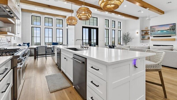 A modern kitchen with white cabinetry, a large island, and pendant lighting. - Driftwood Waves 116 LES (Port Aransas)