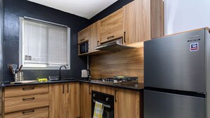 A modern kitchen with wooden cabinets, a stainless steel refrigerator, a microwave, and a gas stove.
