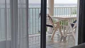 Ein Balkon mit Tisch und Stühlen, mit Blick auf das Meer.