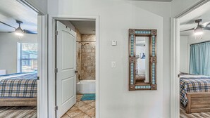 Una habitación de hotel con piso de madera, baño con ducha y cama con colcha escocesa.