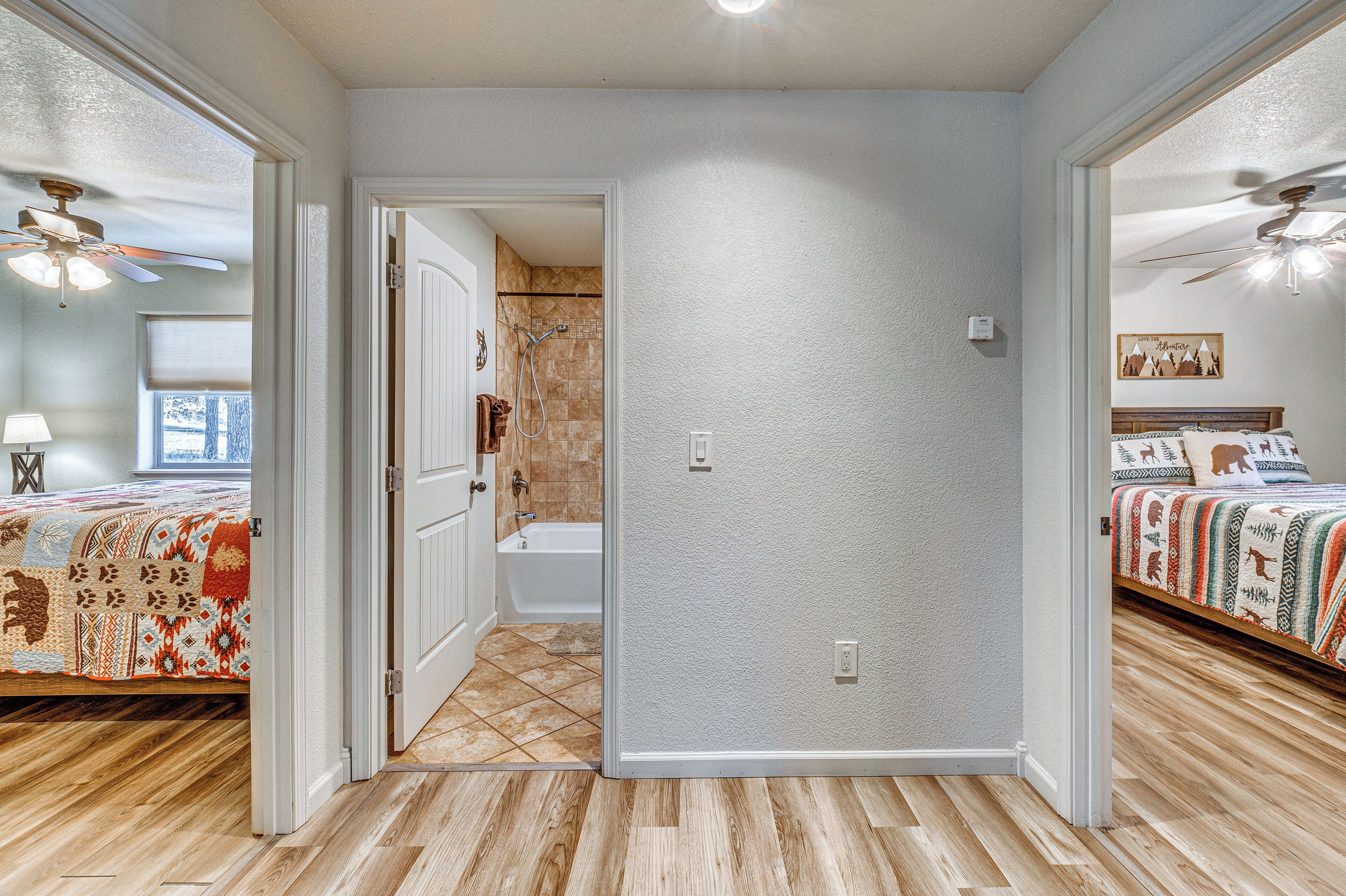 Un dormitorio con una cama, una mesita de noche, un ventanal y una puerta que da a un baño.