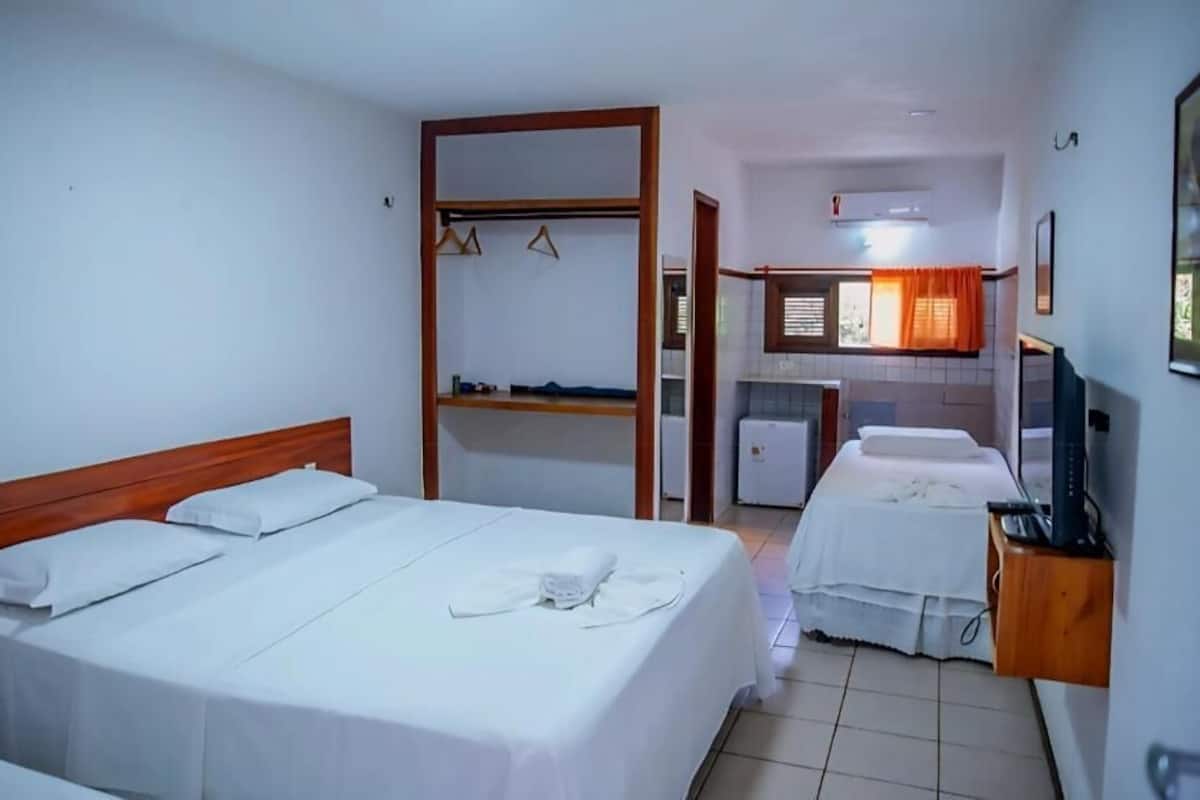 Ett hotellrum med två sängar, ett litet kök och en TV.
