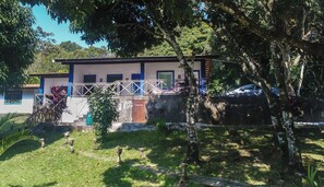 A building with a balcony, a stone wall, and a car parked nearby. - Hotel Fazenda Portal das Montanhas (Pacoti)