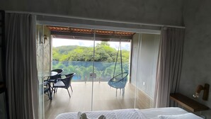 Une chambre à coucher comprenant un lit, une petite table, deux chaises et un balcon avec vue sur la verdure.