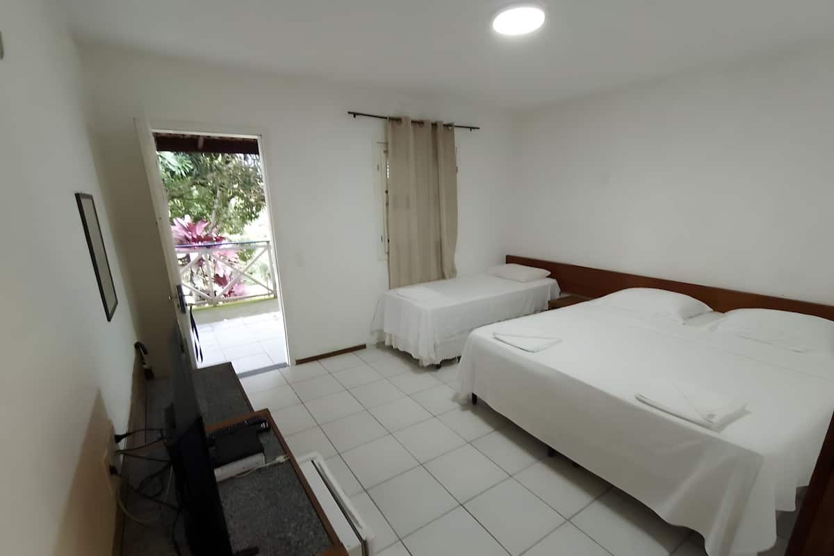 Ett hotellrum med två sängar, ett skrivbord och utsikt över grönområden utanför.