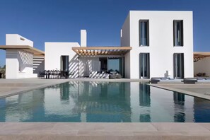 Uma casa moderna com piscina, área de estar externa e pérgola.