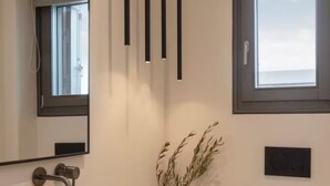 A modern bathroom with a large stone sink, a toilet, a window, and a mirror. - Celestial Villa I (Santa Maria)