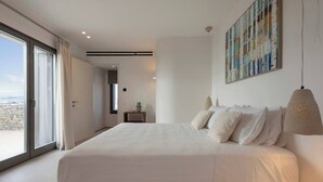 A modern bedroom with a large bed, a view through the sliding doors, and a painting on the wall. - Celestial Villa I (Santa Maria)