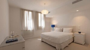 Ein modernes Schlafzimmer mit einem großen Bett, einem Nachttisch, einer Lampe und einem Fenster mit Vorhängen.