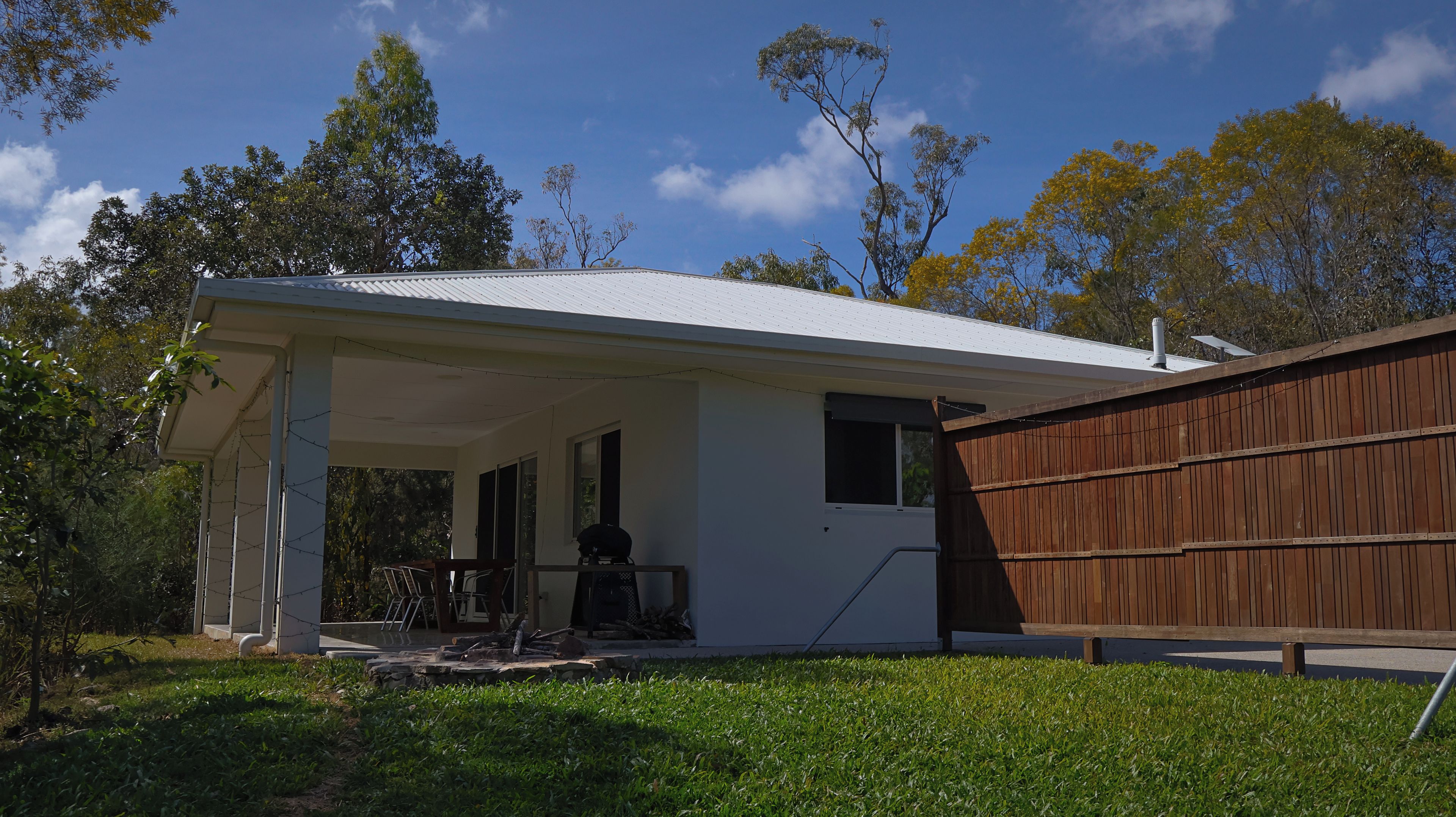 A house with a covered porch, a wooden fence, and a lawn.