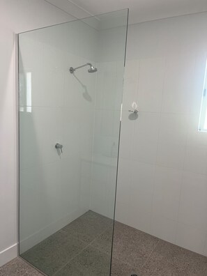 Een douche, handdoeken, zeep, toiletpapier