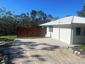 Un bâtiment moderne avec une allée en béton, une clôture en bois et un chemin de gravier.