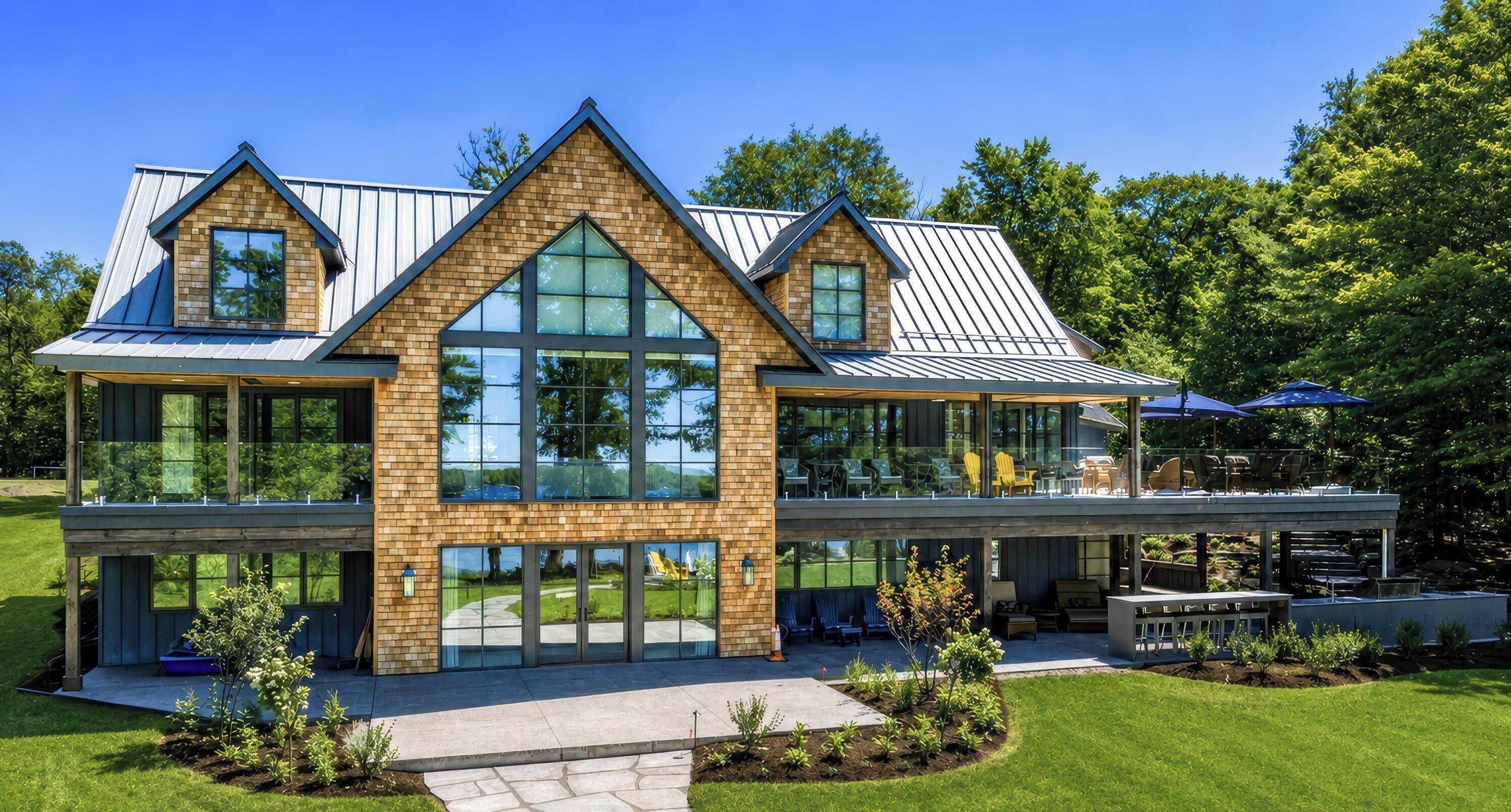 Une maison moderne à deux étages, dotée de grandes fenêtres, d’un patio couvert et d’une pelouse bien entretenue.