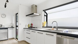 Een moderne keuken met witte kasten, een zwart aanrecht, roestvrijstalen apparatuur en een raam boven de gootsteen.