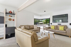 Un salon moderne avec un canapé beige, une table basse et un téléviseur fixé au mur.