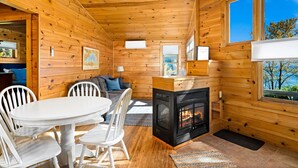 A cozy cabin interior with a dining area, a sofa, a fireplace, and a view of the outdoors. - Charming cabin only feet from Lake Superior (Two Harbors)