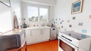 A kitchen with white cabinets, a double sink, a coffee maker, a toaster, and a stove. - Le Tassigny (Saint-Gilles-Croix-de-Vie)