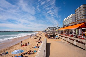 A beach with a promenade, beach umbrellas, and a building with a red awning. - Tassigny - Near Grande Plage, with a garage (Saint-Gilles-Croix-de-Vie)