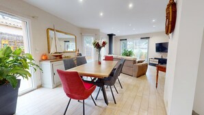 A modern kitchen with a dining area, large windows, and a flat-screen TV. - La Villa du Rocher Vert (Saint-Brevin-les-Pins)