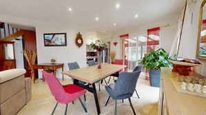 Un coin repas avec une table en bois, quatre chaises, un vase de fleurs et une horloge au mur.