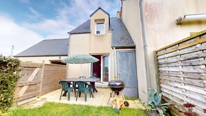 A backyard with a barbecue grill, a wooden fence, and a patio table with chairs. - Escapade Turballaise - House 400m from the Port (La Turballe)
