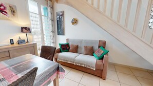 Una sala de estar acogedora con un sofá, una mesa de comedor y una escalera.