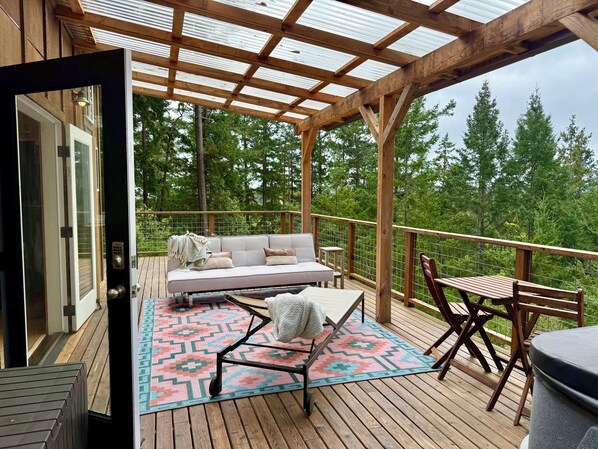 Une terrasse en bois avec un canapé, une table et des chaises, donnant sur une forêt.