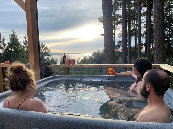 Un bain à remous avec vue sur une forêt et un plan d’eau.