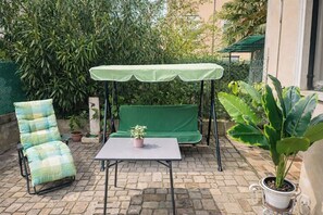 A patio with a green swing, a cushioned chair, a table, and a potted plant. - Venice Mestre Private Home - (Easy Access to Venice) (Venezia)