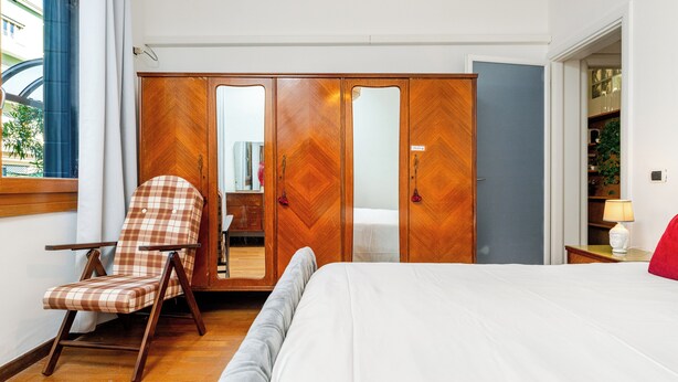 A bedroom with a bed, a wooden wardrobe with mirrored doors, a chair, and a bedside table with a lamp. - Venice Mestre Private Home - (Easy Access to Venice) (Venezia)