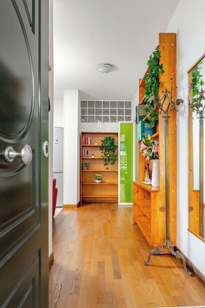 A hallway with a wooden floor, a green door, and a bookshelf with books and plants. - Venice Mestre Private Home - (Easy Access to Venice) (Venezia)