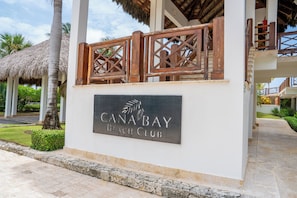 Schild für den Canabay Beach Club, im Hintergrund ein Palmenbaum und eine Struktur mit einem Reetdach.