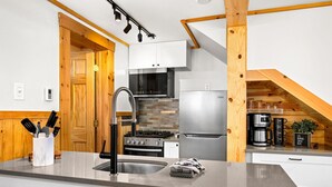 Una cocina moderna con un lavamanos de acero inoxidable, una estufa empotrada y un refrigerador.