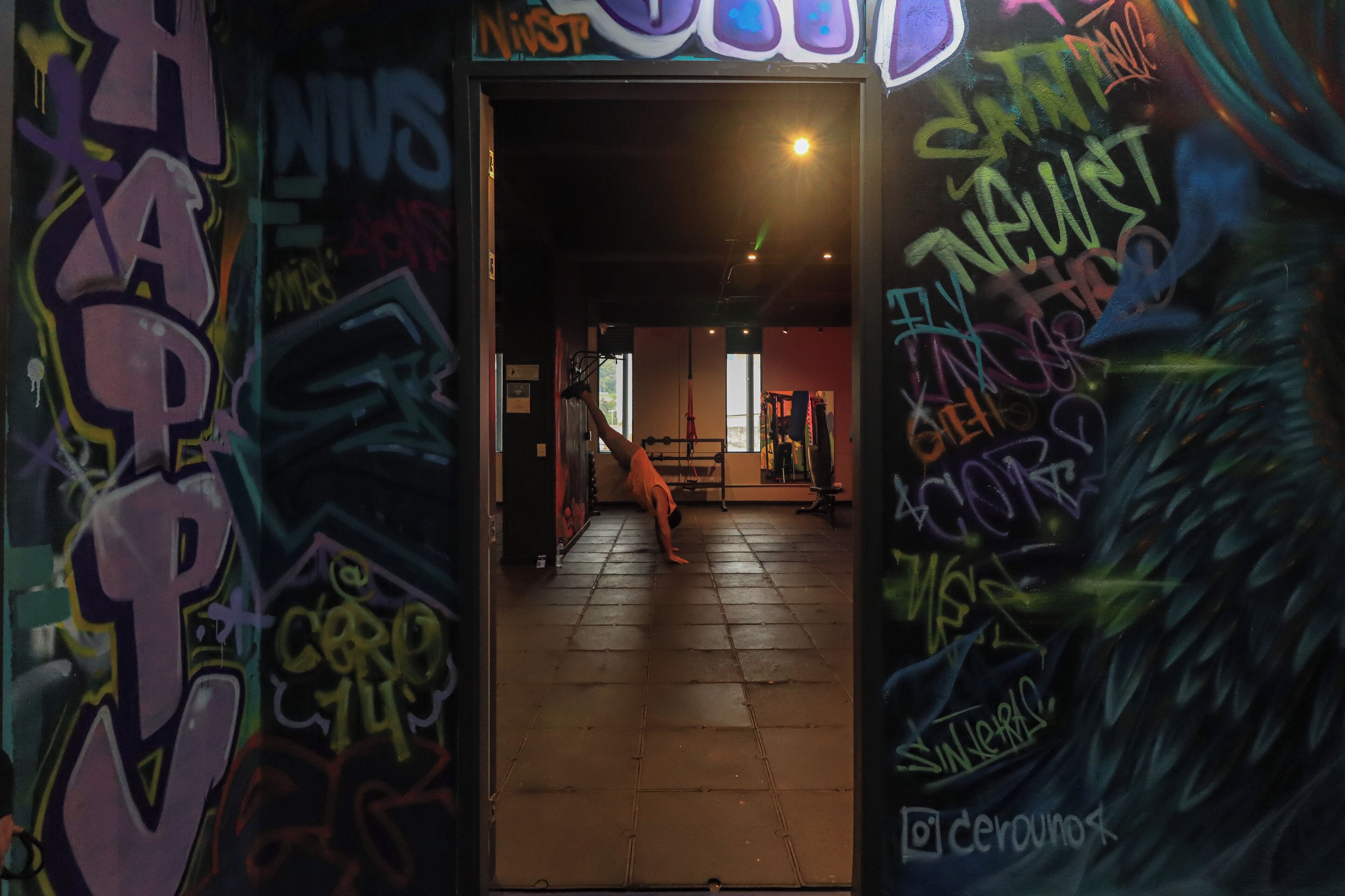 Sisätila, jonka seinät on koristeltu graffiteilla, ja jossa henkilö on päälläseisontatehden.