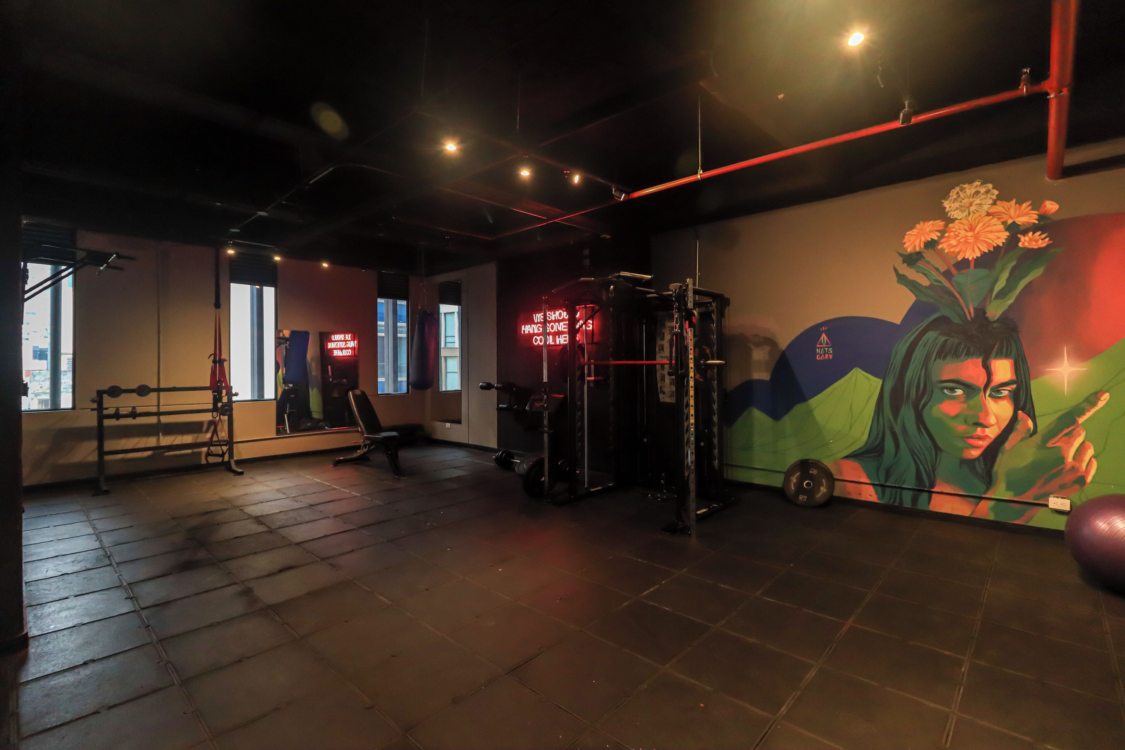 A gym with exercise equipment, a mirror, and a mural on the wall.