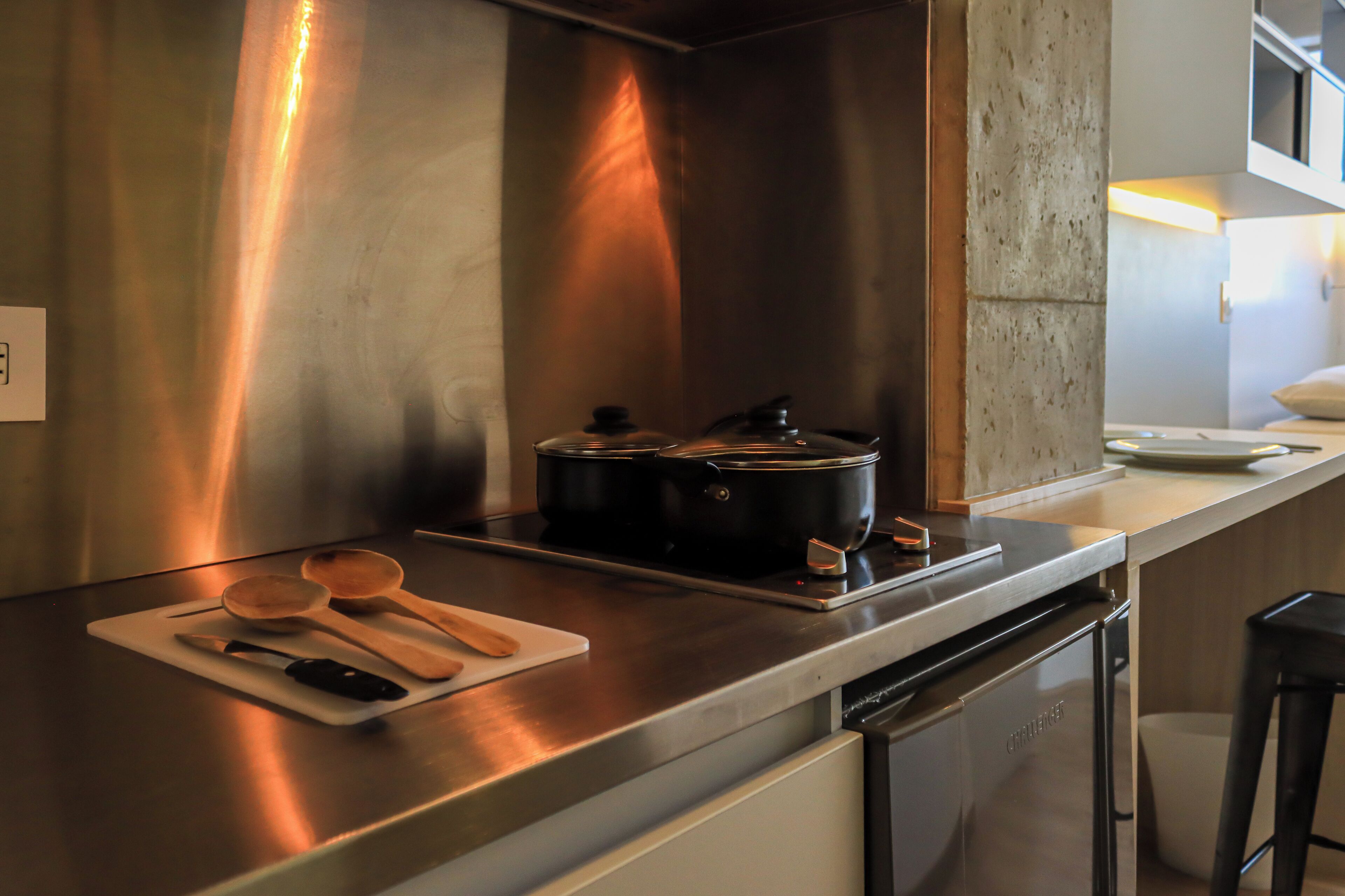 Une cuisine moderne équipée d’appareils électroménagers en acier inoxydable, d’ustensiles de cuisine en bois posés sur une planche à découper et d’un lave-vaisselle.