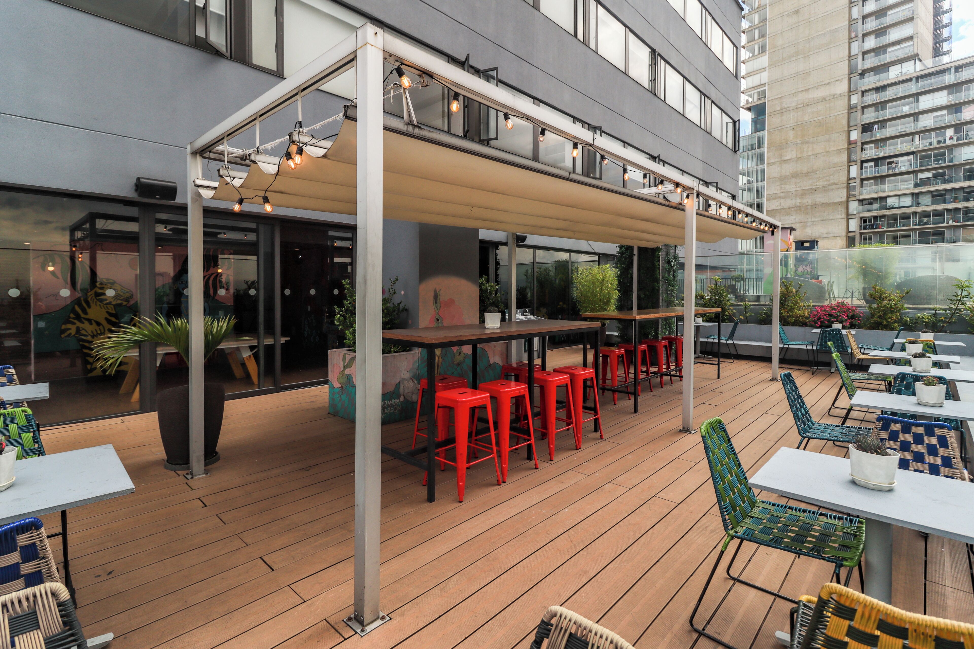 An outdoor seating area with tables and chairs, a covered section, and a view of a building in the background.