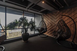 A modern interior with a large window, a potted plant, and two hanging chairs. - Happa Hub (Bogotá)