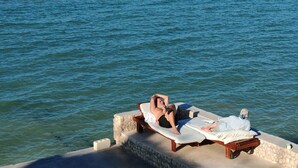 Un homme se détend sur une chaise longue au bord de la mer.